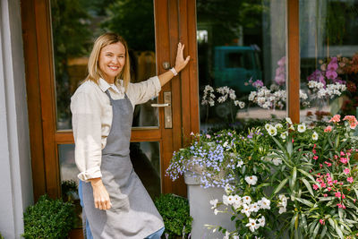 Portrait of young woman standing against plants