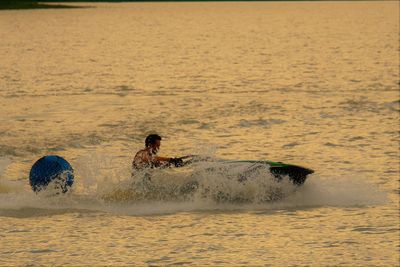 High angle view of man jet boating in sea during sunset