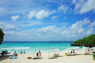 People at beach against blue sky