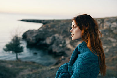 Beautiful woman standing on rock at beach against sky