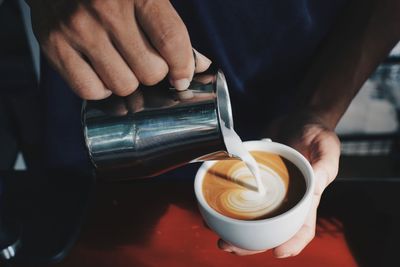 Midsection of man holding coffee on table