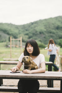 Portrait of smiling woman with dog statue sitting at picnic table 