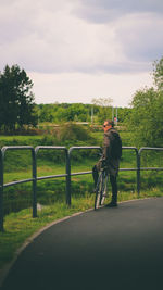 Rear view of man riding bicycle on road against sky