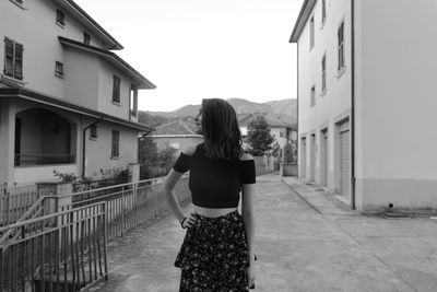 Rear view of woman standing on building against clear sky