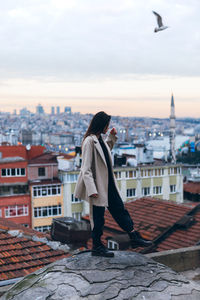 Woman standing by buildings against sky in city