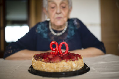 Portrait of senior woman blowing out the candles on her birthday cake