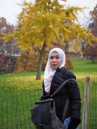 Portrait of mature woman standing against trees in park during autumn