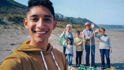 Portrait of smiling young man with family cleaning beach