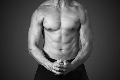 Midsection of muscular man against black background