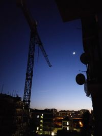 Low angle view of illuminated crane against sky at night