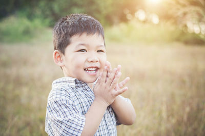 Cheerful boy carried by parents against sky