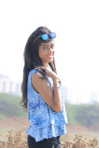 Portrait of smiling young woman against clear sky