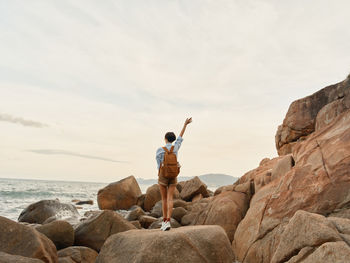 Rear view of man standing on rock at beach