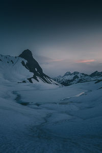 Scenic view of snow covered mountains against sky during sunset