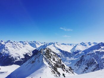 Scenic view of snowcapped mountains against blue sky