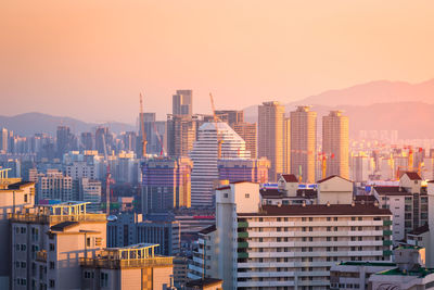 Modern buildings in city against clear sky during sunset