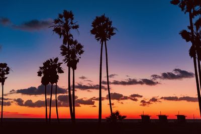 Silhouette palm trees against romantic sky at sunset