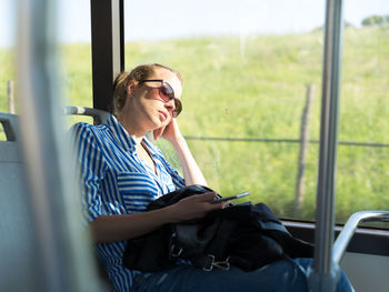 Woman looking at camera while sitting on window