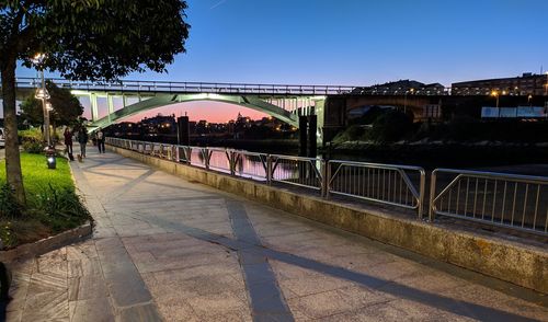 Bridge over river in city against clear sky