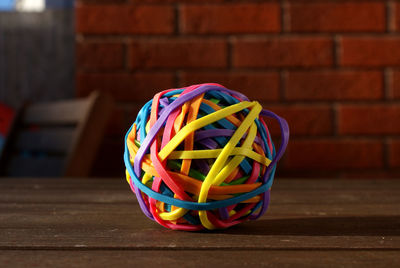 Close-up of colorful rubbers on wooden table against brick wall