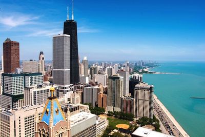 High angle view of city by sea against blue sky