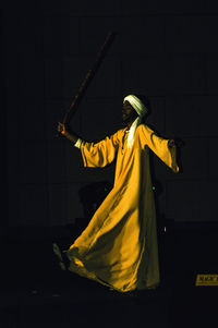 Woman standing by yellow light against gray background