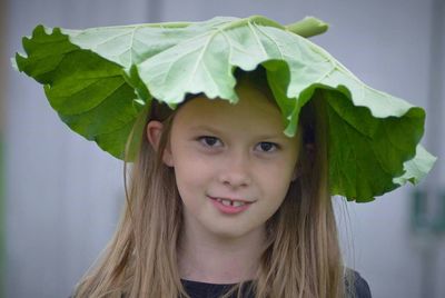 Portrait of woman with huge leaf standing outdoors