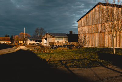 Plants growing on field by buildings against sky