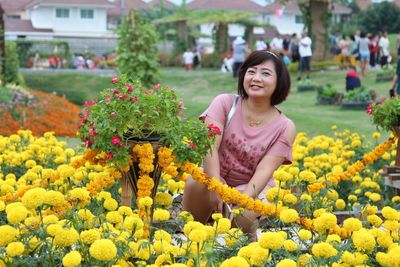 Portrait of smiling woman by yellow flowers at park