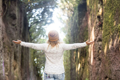 Rear view of woman standing by tree in forest