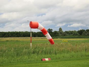 Red umbrella on field against sky