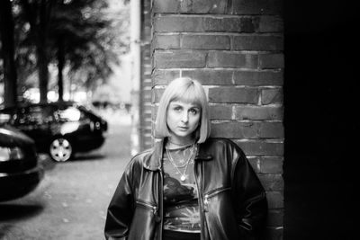 Portrait of young woman standing against wall