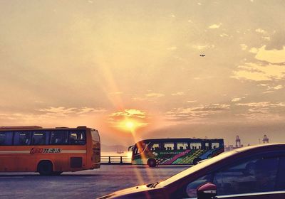 Cars on road in city against sky during sunset