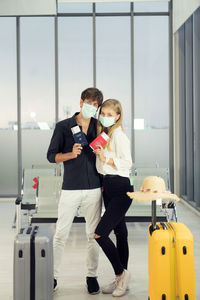 Life during covid-19 pandemic. young man and woman waiting for flying at airport at window