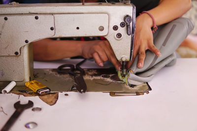 Midsection of woman using sewing machine on table