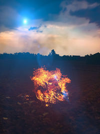 Bonfire on field against sky at sunset