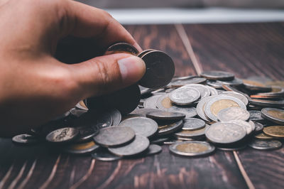 Cropped hand of man holding coins on table