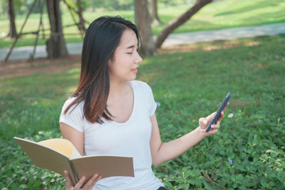 Young woman using mobile phone on field