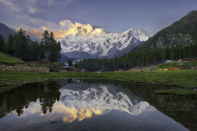 Scenic view of lake by snowcapped mountains against sky