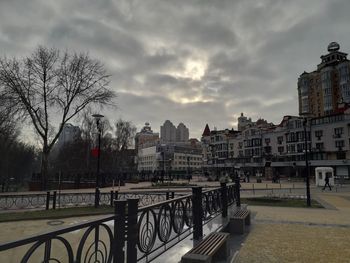 Buildings by river against sky in city