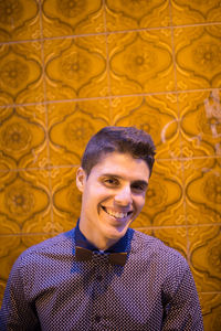 Portrait of smiling young man standing against tiled wall