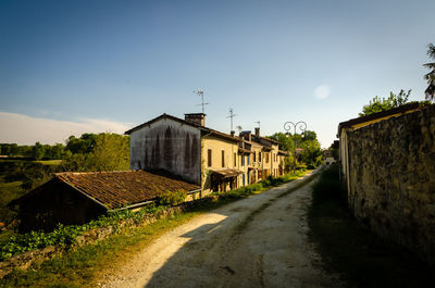 Houses by road amidst buildings against sky