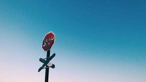 Low angle view of road sign against clear blue sky