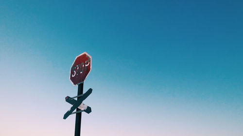 Low angle view of stop sign against clear blue sky