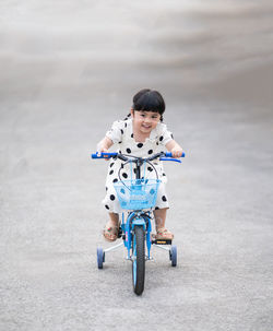 Portrait of boy playing with push scooter on road