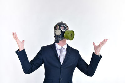 Well-dressed businessman wearing gas mask against white background