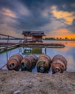 Built structure on lake against sky during sunset