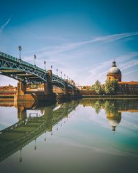 Arch bridge over river in city against sky