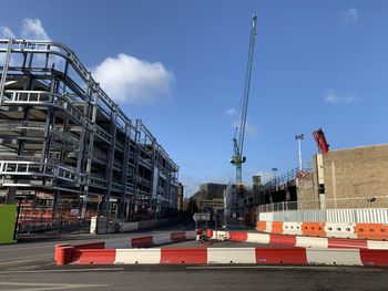 Cranes at construction site against sky in city