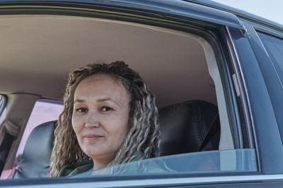 Close-up portrait of cute smiling middle aged asian woman in open car window.